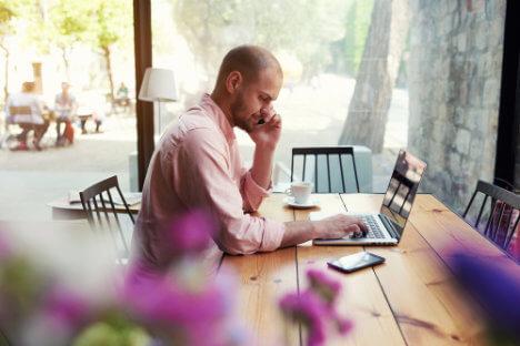 Man-sits-behind-computer-on-phone-and-tablet